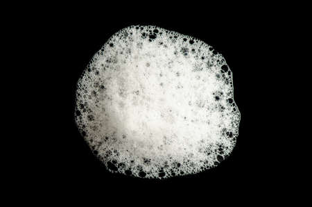 Texture of white foam on a black background. Cleansing mousse for the face or shower gel or washing...