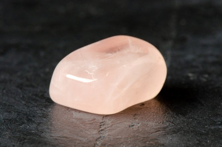 The mineral rose quartz on a black concrete background. The concept of using minerals and crystals...
