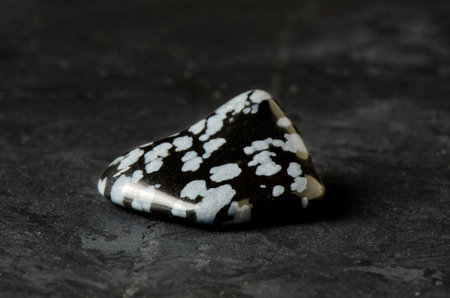 Stone mineral obsidian on a black concrete background. The concept of using minerals and crystals in astrology and alternative or complementary medicine.の写真素材