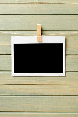An empty photo is hanging on a rope. A design element. Wooden background. Copy space.の写真素材