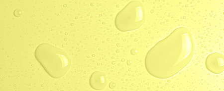Drops of micellar water or cosmetic tonic on a yellow background. Closeup, macro photographyの写真素材