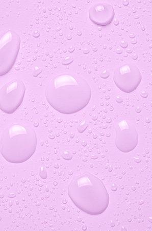 Drops of micellar water or cosmetic tonic on a pink background. Close-up, macro photographyの写真素材