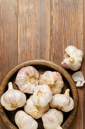 Garlic in a wooden plate. Brown wooden background. Copy space.の写真素材