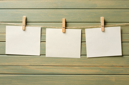 Empty paper sheets hang on a rope. A design element. Wooden background. Copy space.の写真素材