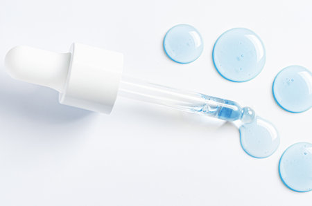 Drops of cosmetic serum and a pipette. A skin care product. White background. Copy space.
