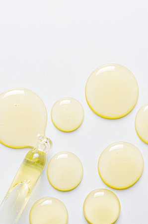 Drops of cosmetic serum and a pipette. A skin care product. White background. Copy space.