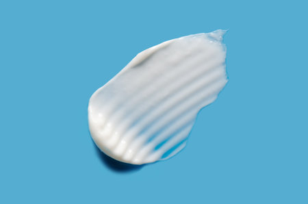A sample of white cosmetic moisturizer on a blue background.