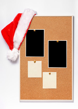 Blank paper notes and an empty photo are pinned to a cork board. Santa's hat on a cork board.の写真素材