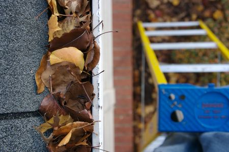 A fall tradition - cleaning the gutters of leaves. Here, we see them clogging the gutters of a traditional home. Could be used for advertising/clean up articles/etc. Narrow DOFの写真素材