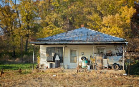 The sun sets on an old abandoned house with fall leaves in the backgroundの写真素材