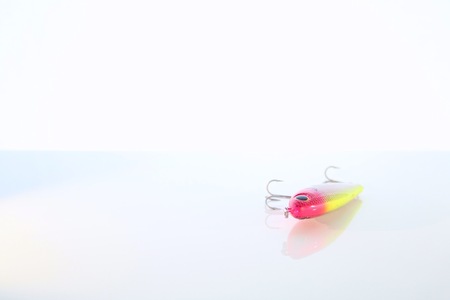 Red and Yellow Fishing Lure with Reflection on White Table Topの写真素材