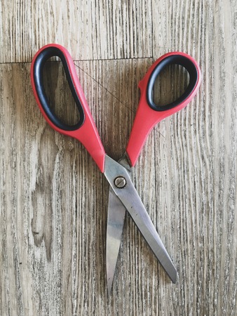 Red scissors closed on a wooden tableの写真素材