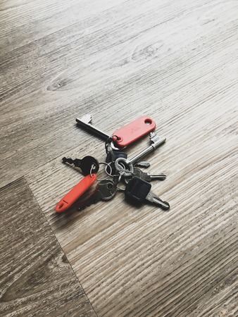 Bunch of keys on a wooden surface with red tags.の写真素材