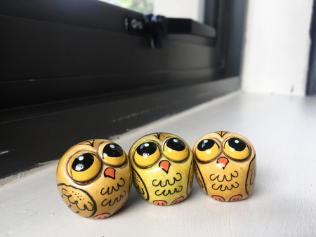 Three yellow owls on a shelf in the sun.の写真素材