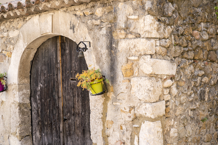 old wooden gate with small yellow plant on a stone wallの写真素材
