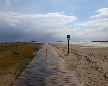 Wooden jetty at the North Sea near sankt Peter Ording with clouds and sand and seaの写真素材