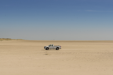 suv alone on an endless beach and a blue sky in the North Seaの写真素材