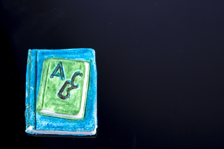 small book as decoration with the letters ABC on a black background and free space for text for school starterの写真素材