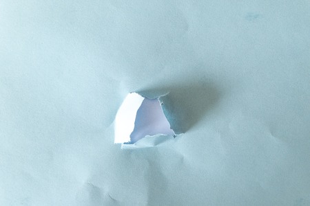 hole torn in blue paper on white background as patternの写真素材