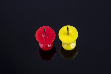 two pins in the color red and yellow against black background