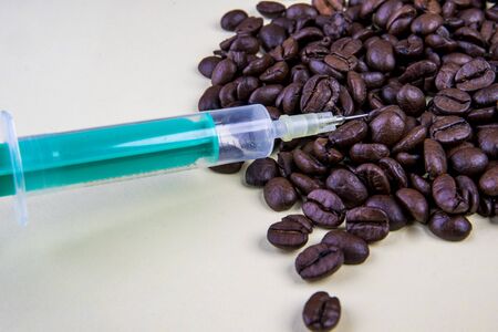 Caffeine syringe with coffee beans on beigeの写真素材