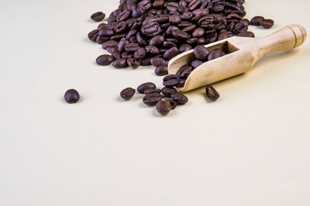 Coffee beans on beige background with wooden spoonの写真素材