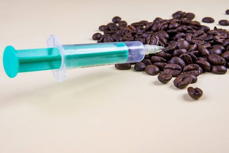 Caffeine syringe with coffee beans on beigeの写真素材
