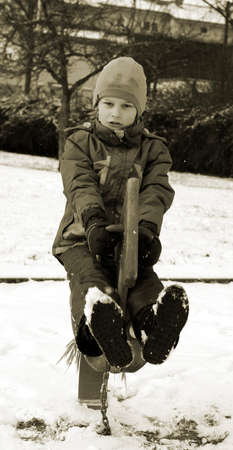 Black and white picture child on the rocking horse in the snowの写真素材