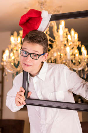 Boy with glasses and white shirt in front of festive candlestick and Christmas hatの写真素材