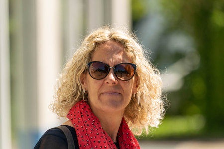Woman smiling at the camera with blonde curls and sunglassesの写真素材