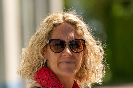 Woman smiling at the camera with blonde curls and sunglassesの写真素材