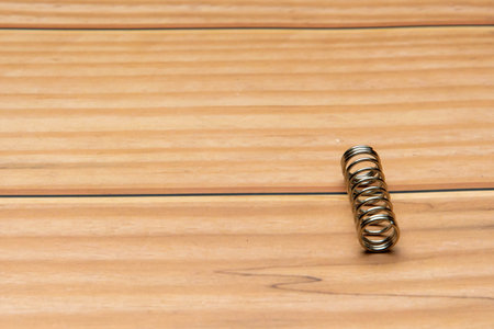 Metal spring on a wooden background, close-up, selective focusの写真素材