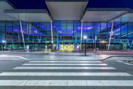 Wroclaw, Poland - June 17, 2020: Zebra crossing in front of modern building of Wroclaw Airport terminal at dusk. Entrance to arrivals hall thorough street. Airport at nightのeditorial素材