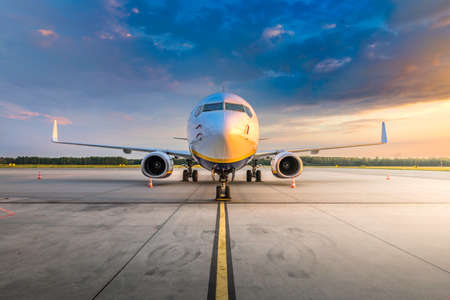 Modern commercial airplane in the parking lot of the airport apron, waiting for services maintenance, refilling fuel, and passenger boarding the plane. Concept of travel, holidays and business jetの写真素材