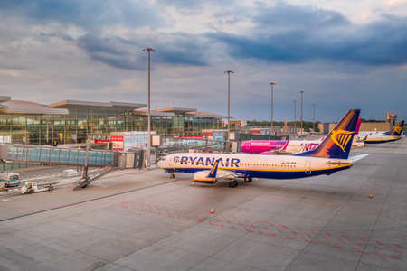 Wroclaw, Poland - June 17, 2020: Comercial airplane seen from the side in the parking lot of the airport apron in front of modern Wroclaw Airport terminal at cloudy afternoon, waiting for serviceのeditorial素材