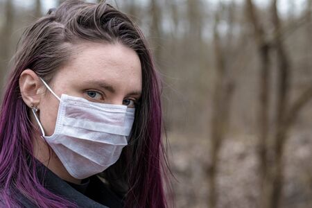 Yong woman in park in protective medical mask for face protection against virus outbreakの写真素材