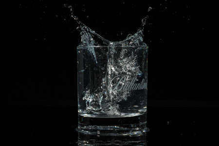 VARNA, BULGARIA - MARCH 31, 2020: Ballantines glass filled with liquid with an ice cube dropped in. Ballantine's is a range of Blended Scotch whiskies produced by Pernod Ricard in Dumbarton.のeditorial素材