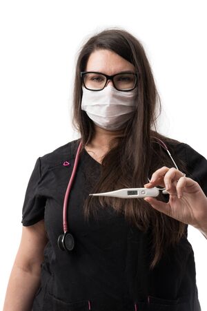 Young female doctor in a black uniform, mask and stethoscope holding a digital thermometer, isolated on white backgroundの写真素材