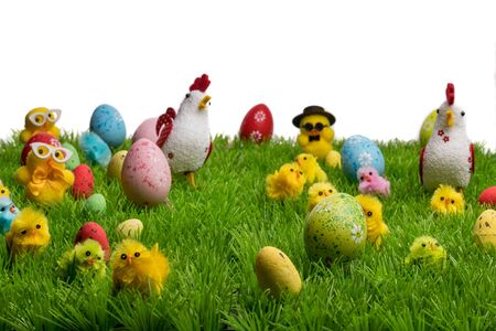 Decorative easter chickens, hens and eggs on plastic grass, forming a festive scene. Isolated on...