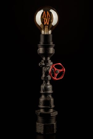 Vintage lamp made from steel water pipe fittings with filament bulb and valve switch, on black backgroundの写真素材
