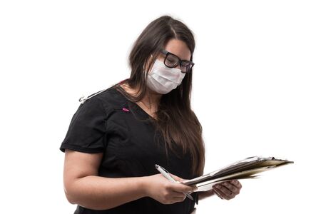 Portrait of a female doctor in black uniform wearing a mask, holding a note pad, isolated on white backgroundの写真素材