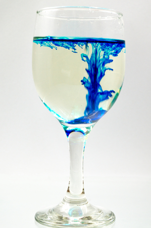 Glass full of water with ink color dropの写真素材