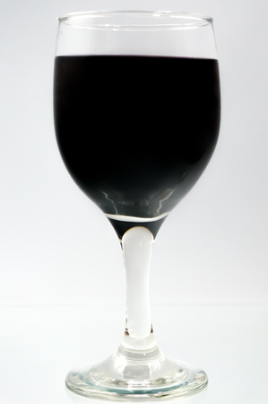 Glass full of water with ink color dropの写真素材