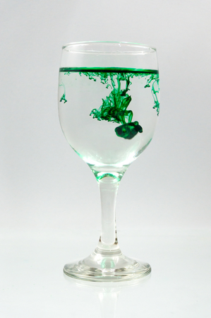 Glass full of water with ink color dropの写真素材