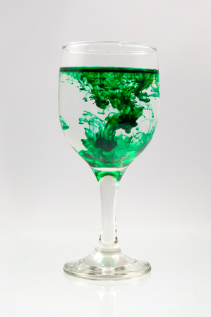Glass full of water with ink color dropの写真素材