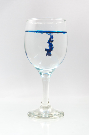 Glass full of water with ink color dropの写真素材
