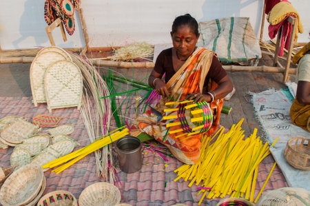 KOLKATA, WEST BENGAL , INDIA - DECEMBER 14TH 2013   Unidentified woman making wicker baskets , handicrafts on display at Handicraft Fair in Kolkata - the biggest handicrafts fair in Asia のeditorial素材
