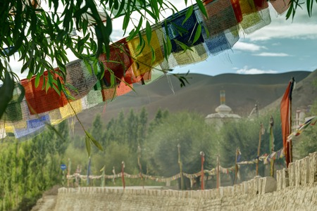 Buddhist religious flags, Play of light and shadow on mountains of Mulbekh, Himalayan mountains with shadow of clouds in background, Ladakh, Jammu and Kashmir, Indiaの写真素材