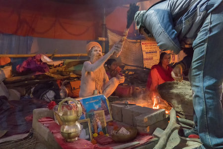 BABUGHAT, KOLKATA, WEST BENGAL / INDIA - 9TH JANUARY 2018 : Indian Hindu Sadhu , sitting with Holy ashes applied all over his body. Blessing a devotee. Shot agsint holy smoke.のeditorial素材