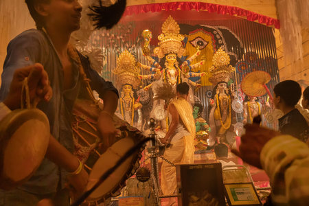 KOLKATA , INDIA - SEPTEMBER 27, 2017 : Young Hindu Priest worshipping Goddess Durga under holy smoke with dhaakis (drummers) performing. Durga Puja - shot at night under colored light .のeditorial素材